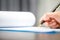 Workplace closeup person professional businesswoman sitting at desk hold pen signing or signature contract paper. Employee woman