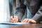 Workplace closeup person professional businesswoman sitting at desk hold pen signing or signature contract paper. Employee woman