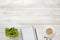 Workplace with cup of coffee, indoor plant, empty notebook and pencil on wooden surface in top view.