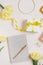 Workplace with a notebook and a pen, yellow tulips, a bracelet, a women`s handbag, eau de toilette on a light background. Flat