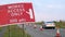 Works access only sign next to roadworks cones flashing on UK motorway at evening with traffic passing