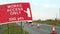 Works access only sign next to roadworks cones flashing on UK motorway at evening with traffic passing