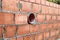 Works on the laying of ceramic bricks. Red brick wall with ventilation hole. Embedded detail in the wall. Progressive construction