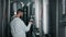 workshop of contemporary craft brewery, man is viewing dark beer in glass, standing between tanks