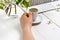 Workspace with girl`s hand on laptop keyboard and cup of coffee, white spring apple tree flowers on white woodden background. Vie