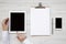 Workspace with tablet, female hands, smartphone and clipboard over white wooden surface, top view. From above, flat lay, overhead