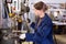 Workwoman drilling metal parts on bench drill