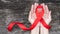 World aids day and national HIV/AIDS and ageing awareness month with red ribbon on woman hand support bow isolated