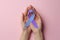 World Arthritis Day. Woman with blue and purple awareness ribbon on pink background, top view