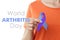 World Arthritis Day. Woman with blue and purple awareness ribbon on white background, closeup