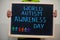 World autism awareness day. Boy hold chalkboard with blue inscription