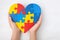 World Autism Awareness day, mental health care concept with puzzle or jigsaw pattern on heart with child`s hands