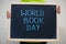 World book day. Boy hold chalkboard with blue inscription