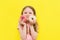 World Donut Day or No diet day. A little girl holding donuts and smiling, holding on a yellow background. The concept. kids and