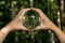 World environmental concept. Crystal globe in human hand on beautiful green and blue bokeh