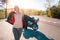 World Motorcyclist Day. A young woman puts on a leather jacket, against the background of a motorcycle by the road