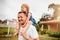 Worlds greatest dad. a mature man carrying his young daughter on his shoulders outside.