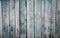 Worn old rough-hewn pine vertical wooden boards with scratches and faded light blue paint.