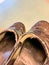 Worn out and damaged slip-on shoes with frayed binding.