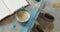 Worn, painted wooden table top with notebook and cup of coffee with milk, slippers below on floor