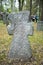 A worn sandstone grave marker in the shade on a very bright day. There is no text visible on the stone, but there is