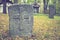 A worn sandstone grave marker in the shade on a very bright day. There is no text visible on the stone, but there is some moss on