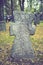 A worn sandstone grave marker in the shade on a very bright day. There is no text visible on the stone, but there is some moss on