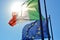 Worn waving flags of Italy and Europe with sun on background