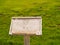 Worn wooden sign in grassy field