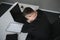 Worried businessman in dark suit sitting at office desk full with books and papers being overloaded with work.