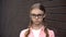 Worried caucasian schoolgirl eyeglasses standing brick wall background, puberty