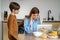 Worried child boy touches mother sitting at kitchen table with laptop from fatigue holding temples