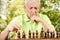 Worried elderly man playing chess outdoors