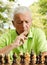 Worried elderly man playing chess outdoors