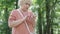 Worried embarrassed senior woman looking around in sunny park or forest and checking online map. Portrait of lost