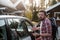 Worried father is standing by an open car and emotionally persuading the whole family to get into a transport as soon as possible