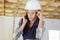 Worried female builder using cellular telephone