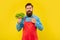 Worried man in apron pointing finger at fresh leaf lettuce yellow background, vegetable vendor