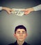Worried man looking up at hands exchanging money