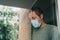 Worried man with protective face mask in self-isolation home quarantine during coronavirus outbreak