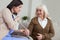 Worried nurse fixing elder woman hand with bandage