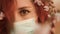 Worried redhead woman wears surgical mask and looks at you. Sakura flowers around head