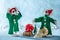 Worried Santas Helper Elf With Head in Hands Standing Next to Another Elf That Broke a Christmas Bauble.North Pole Christmas Scene