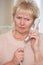 Worried Senior Woman Answering Telephone At Home