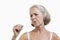 Worried senior woman checking thermometer against white background