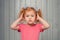 Worried and troubled cute redhead little girl 4-6 years old hold hands on head and frowning upset