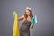 Worried unhappy woman looking at yellow clothes with damage at studio. Stressed housewife holds an iron.