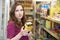 Worried Woman Checking Food Labelling On Box In Supermarket