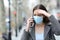 Worried woman with protective mask calling on phone on street