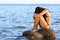 Worried woman sitting on a rock on the beach